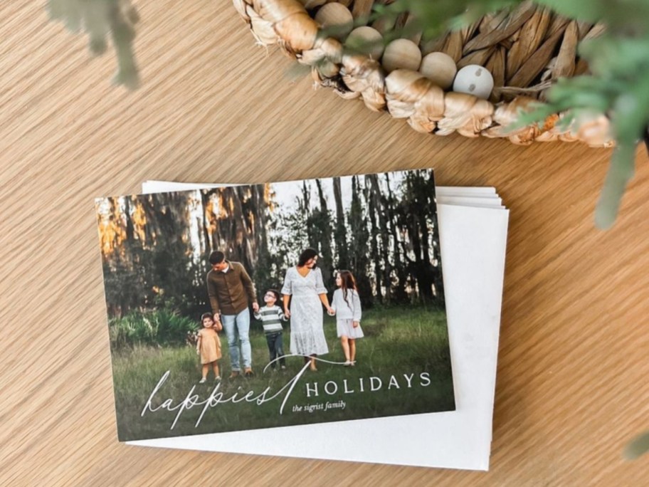 stack of holiday photo cards under Christmas tree