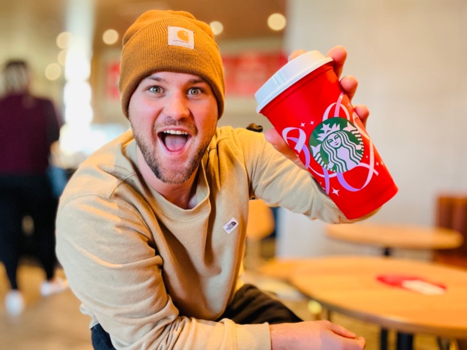 man holding starbucks red cup