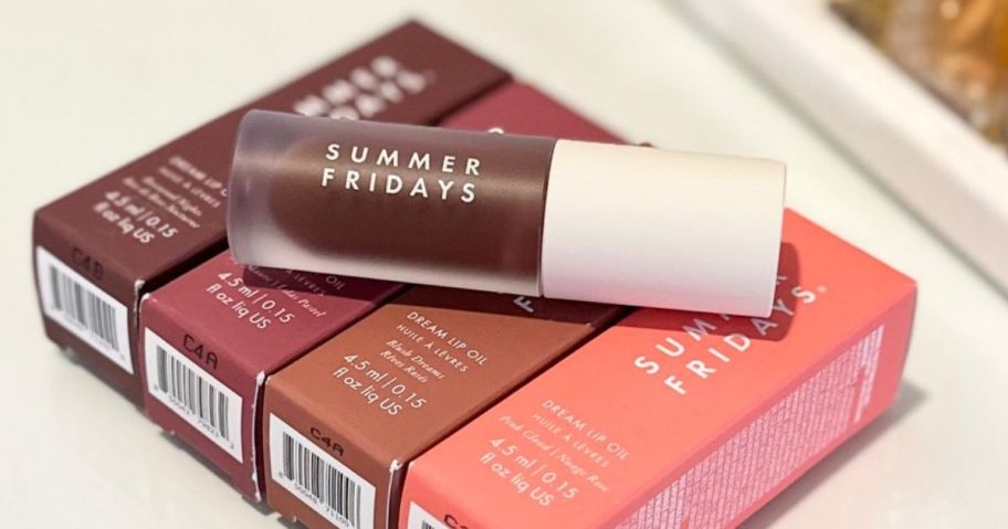 Summer Fridays Dream Lip Oil laying on top of four boxes