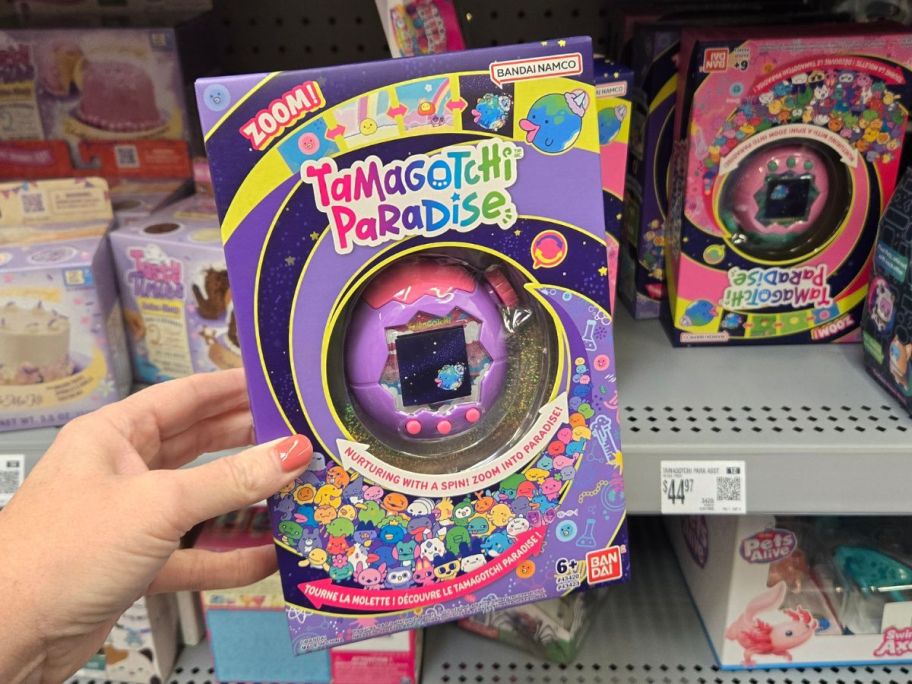 purple tamagotchi toy in hand in store
