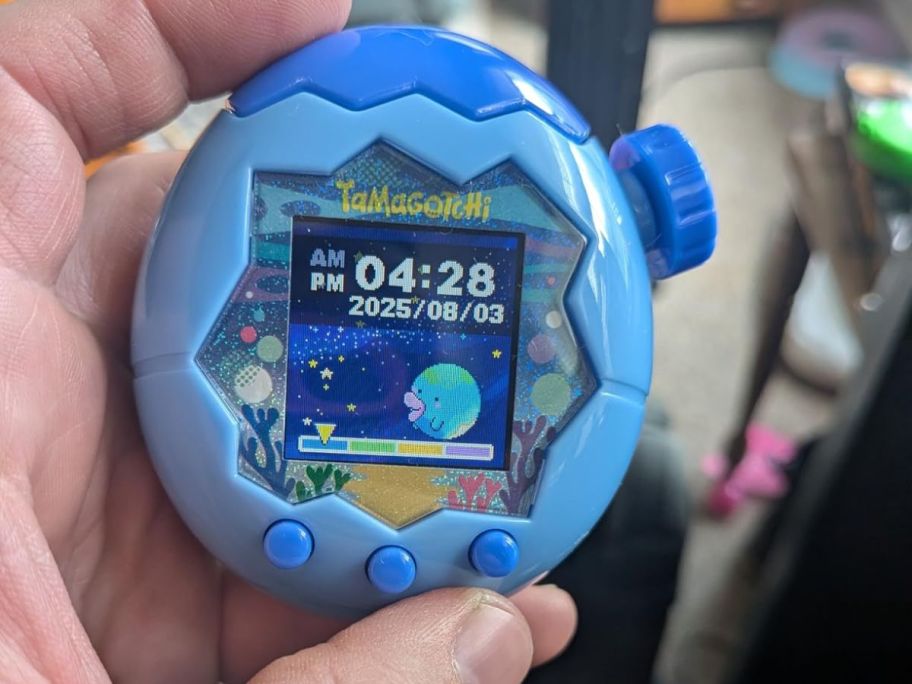 blue tamagotchi toy in hand