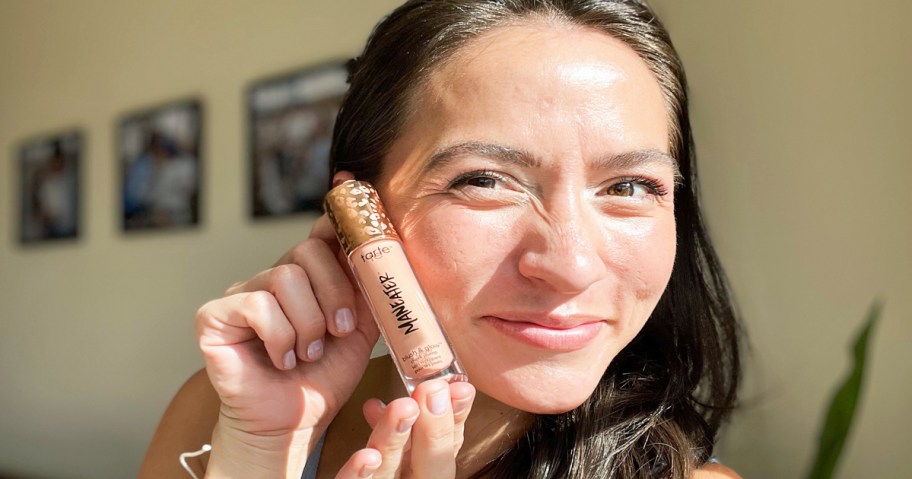 woman holding a tube of tarte Maneater Blush & Glow Cheek Plump next to her cheek