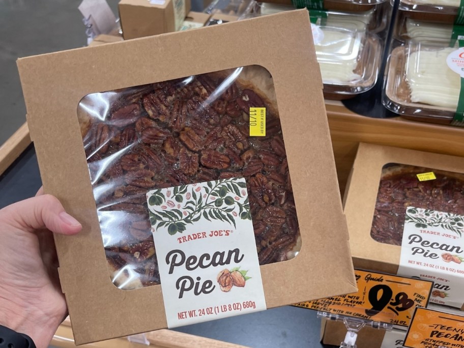 a womans hand holding a boxed pecan pie