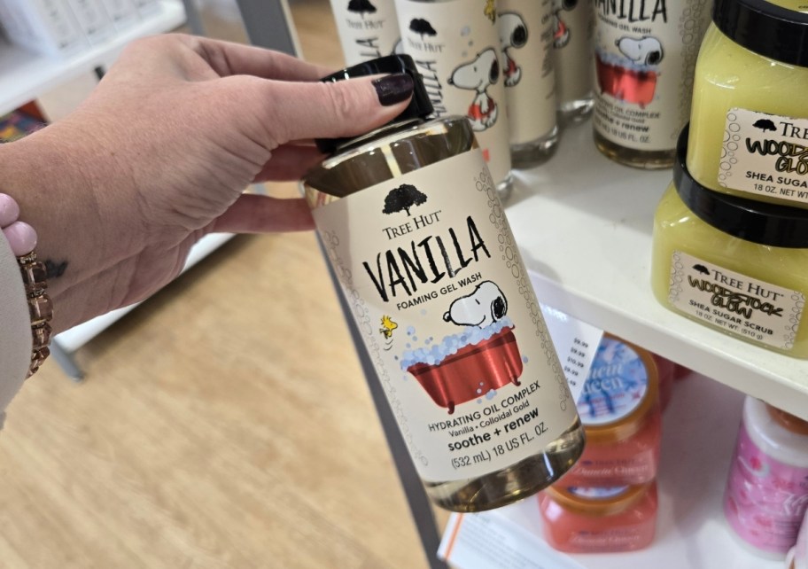 womans hand holding a bottle of foaming bath gel