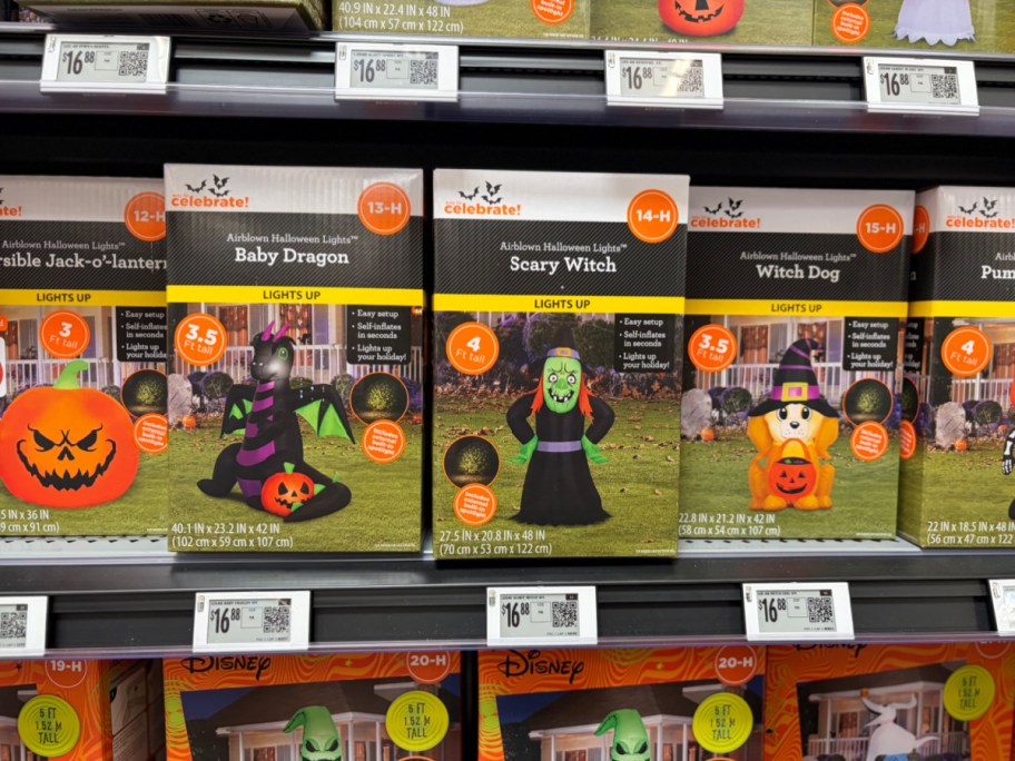 A store shelf featuring Way to Celebrate Halloween inflatable boxes for a baby dragon, a scary witch, and a witch dog.