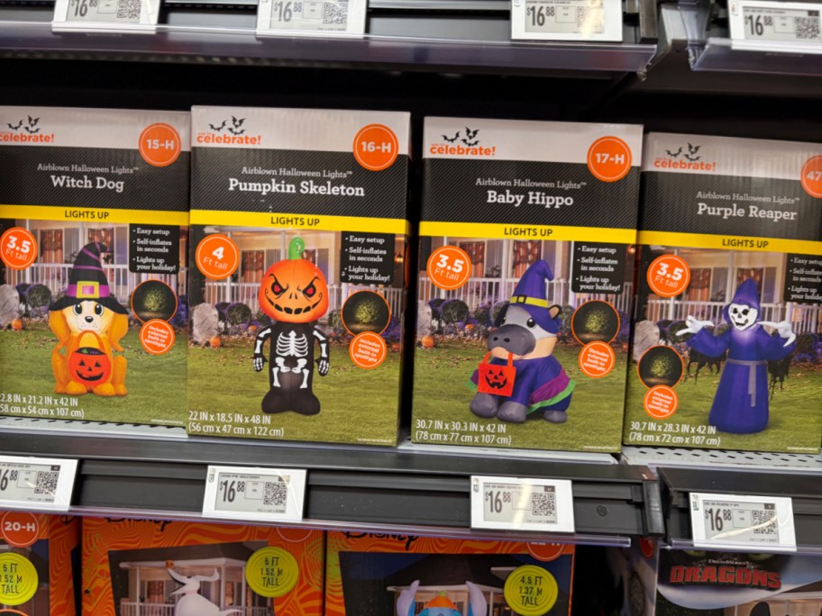 A store shelf of Way to Celebrate Halloween inflatable boxes featuring a Witch Dog, a Pumpkin Skeleton, a Baby Hippo, and a Purple Reaper.