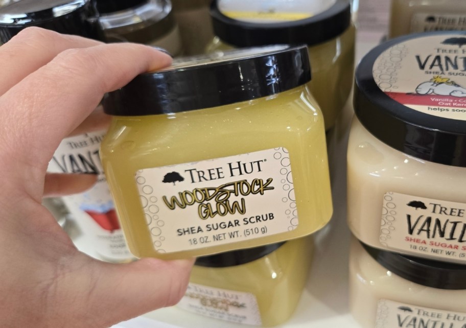 womans hand holding a jar of sugar scrub