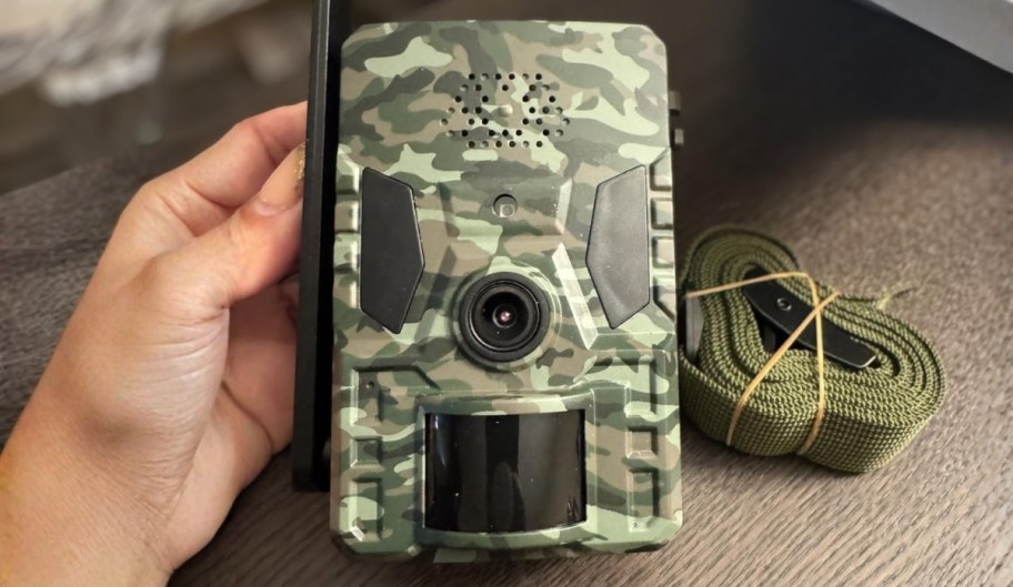 a womans hand holding a trail camera