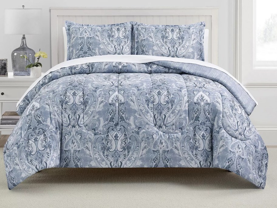 a bed with a blue damask comforter set