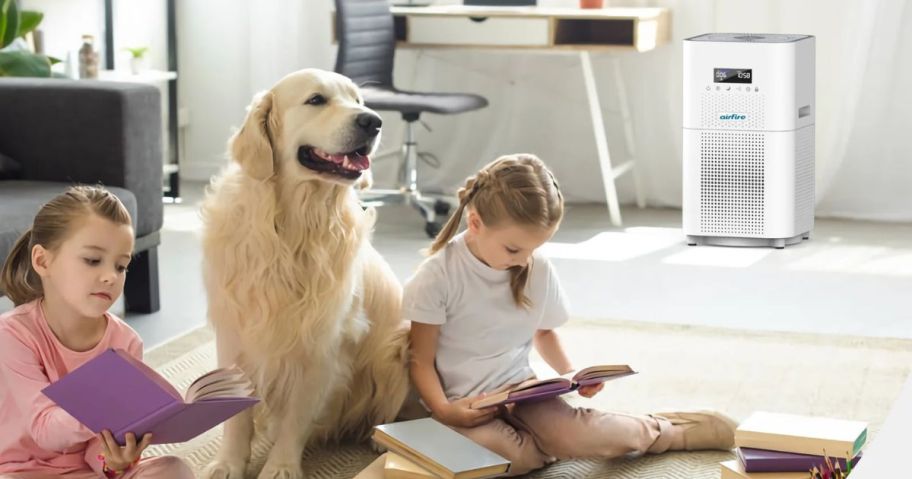 Two little girls and a dog sitting near an air purifier