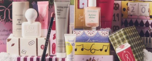 A collection of beauty products from an Anthropologie advent calendar arranged in front of colorful numbered holiday boxes.