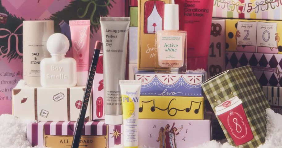 A collection of beauty products from an Anthropologie advent calendar arranged in front of colorful numbered holiday boxes.