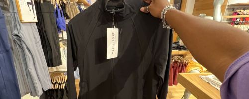 Hand holding a hanger with a black Athleta Athleisure jacket on it