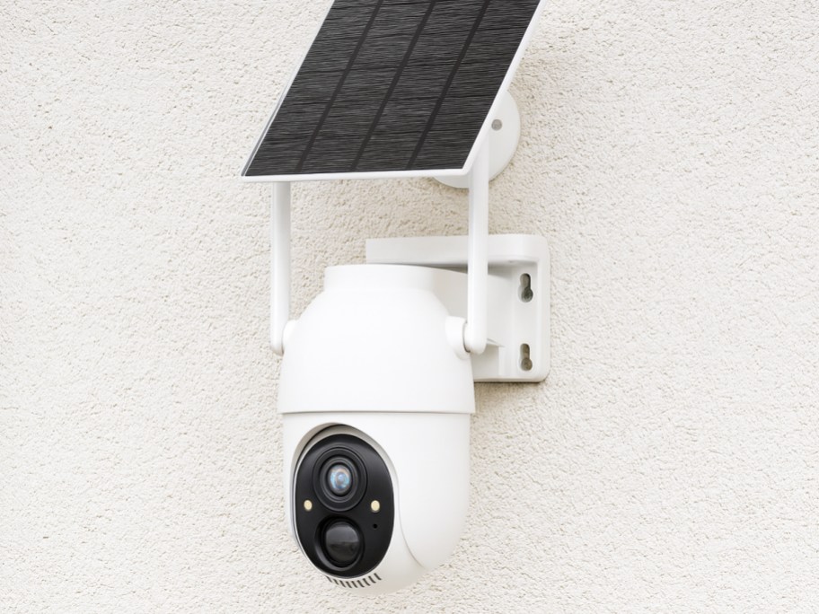 white security camera with solar panel mounted on a wall