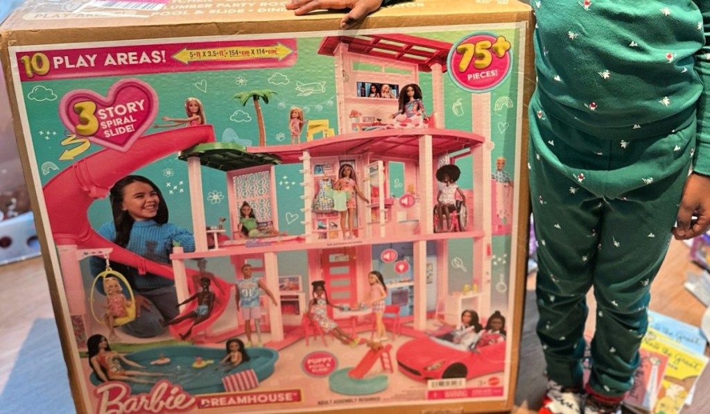 little girl standing next to barbie dreamhouse