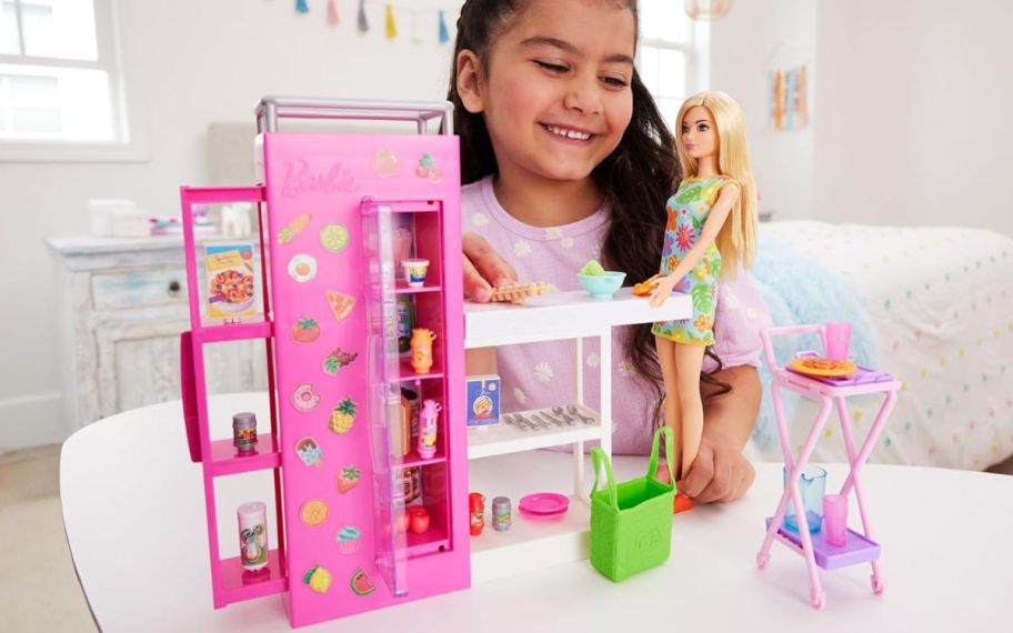 girl playing with Barbie shopper on top of the table