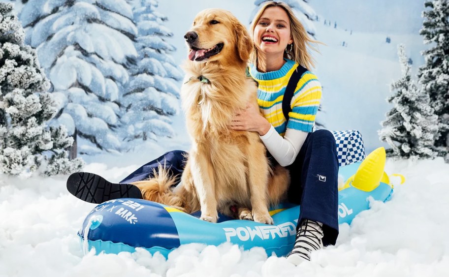woman and golden retriever on a blue sled