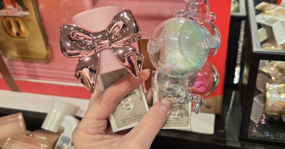 Person holding up pink and white decorated wallflower plugs in Bath & body Works store