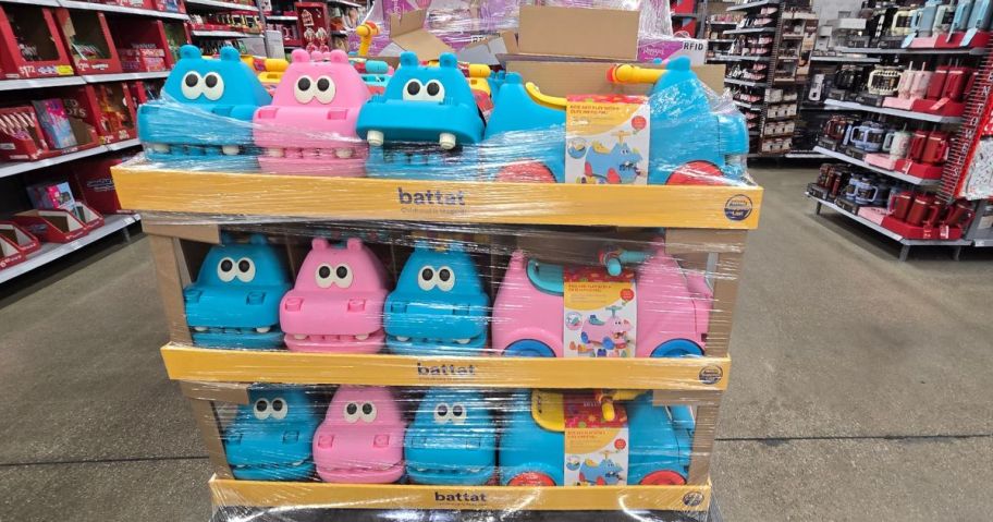 Several plastic blue and pink hippo ride on toys covered in plastic wrap on a skid