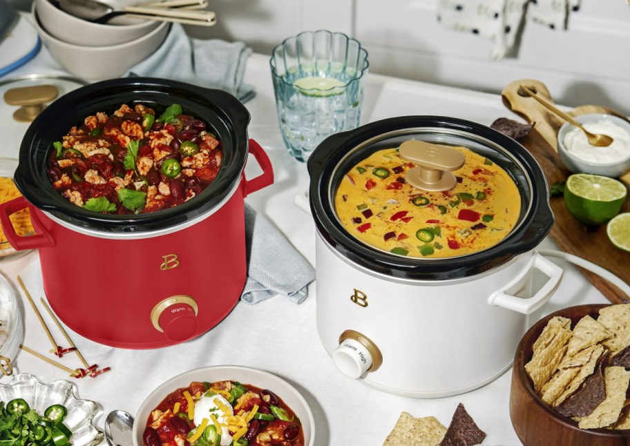 red and white Beautiful Slow Cookers on a table surrounded by food