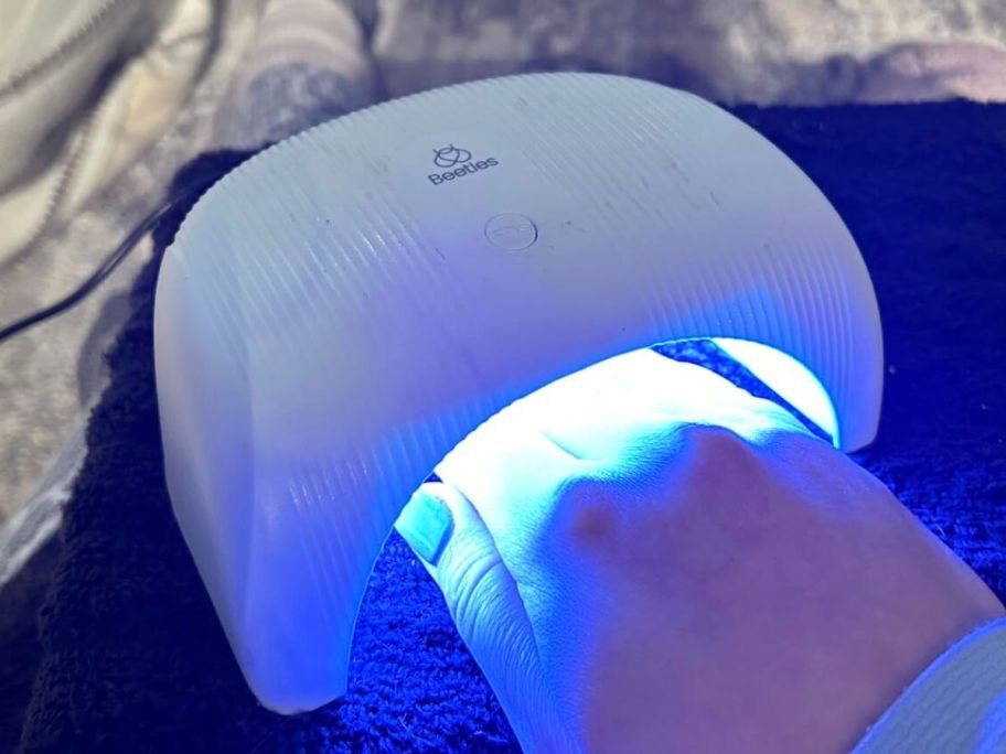 Hand under a Beetles Gel Nail Polish Lamp
