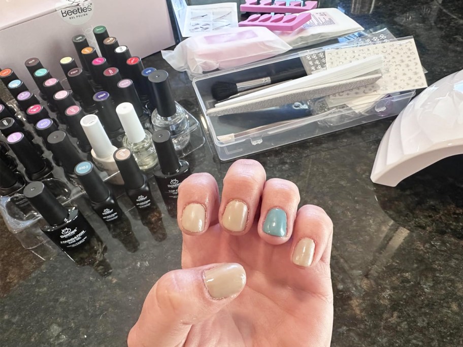 woman showing off gel nails with manicure set in background