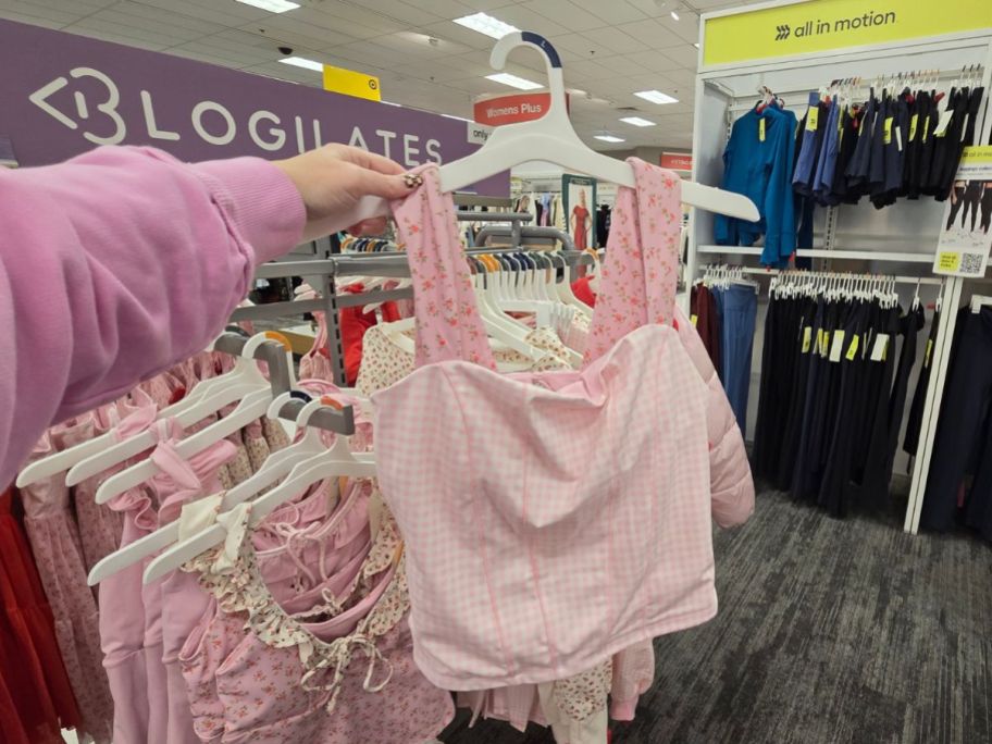 A person holding a pink and white tank top