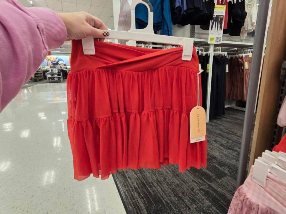 A person holding a red skirt