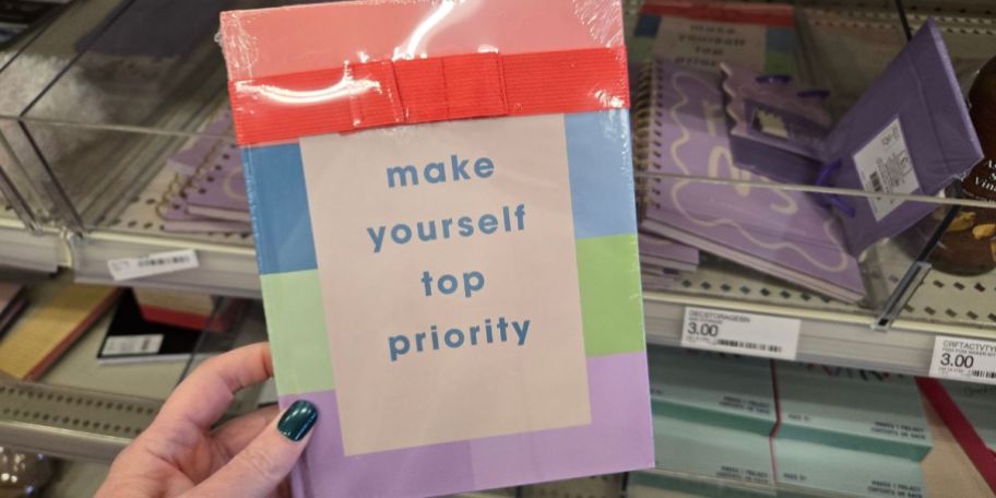 A person holding a multicolored wellness journal titled "Make Yourself top Priority