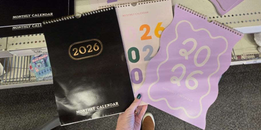 A person holding 3 2026 calendars