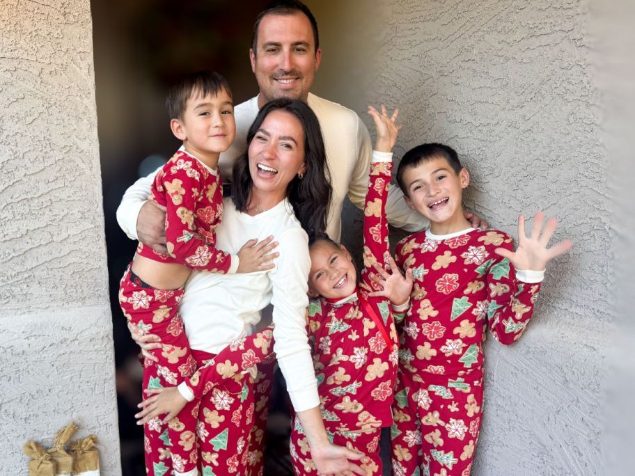 A family wearing Red Burt's Bees Matching Family Pajamas with Gingerbread Cookies on them