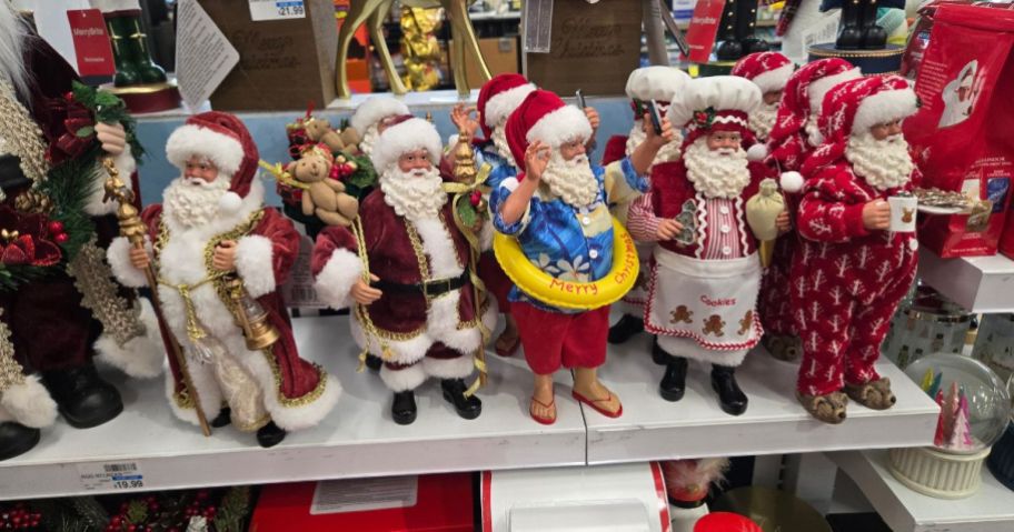 Several Santas in various costumes on a shelf