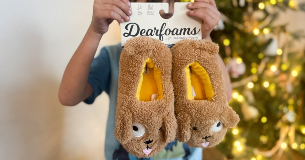 little boy holding up pair of Dearfoams Critter Slippers