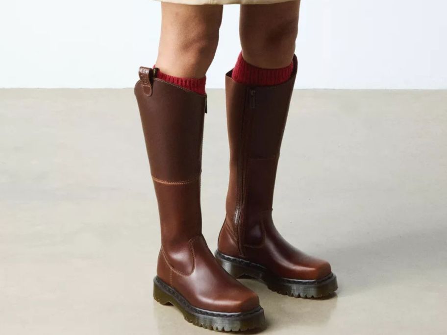 Woman's feet wearing brown Dr. Martens Amaayah Knee High Leather Boots