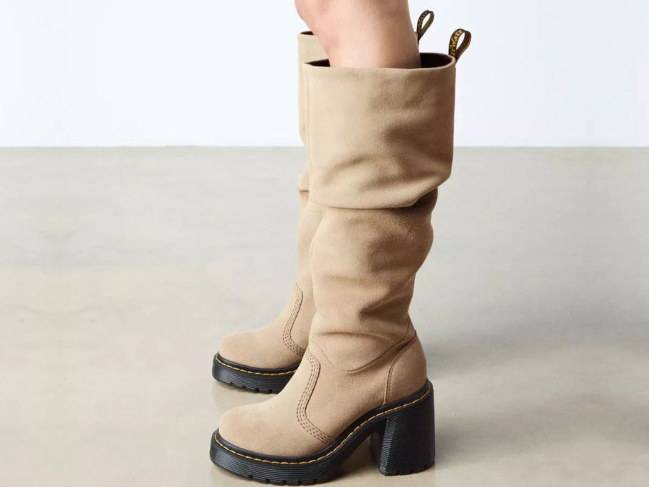 Woman's feet wearing Dr. Martens Kasey Suede Knee High Heeled Boots in Savannah Tan