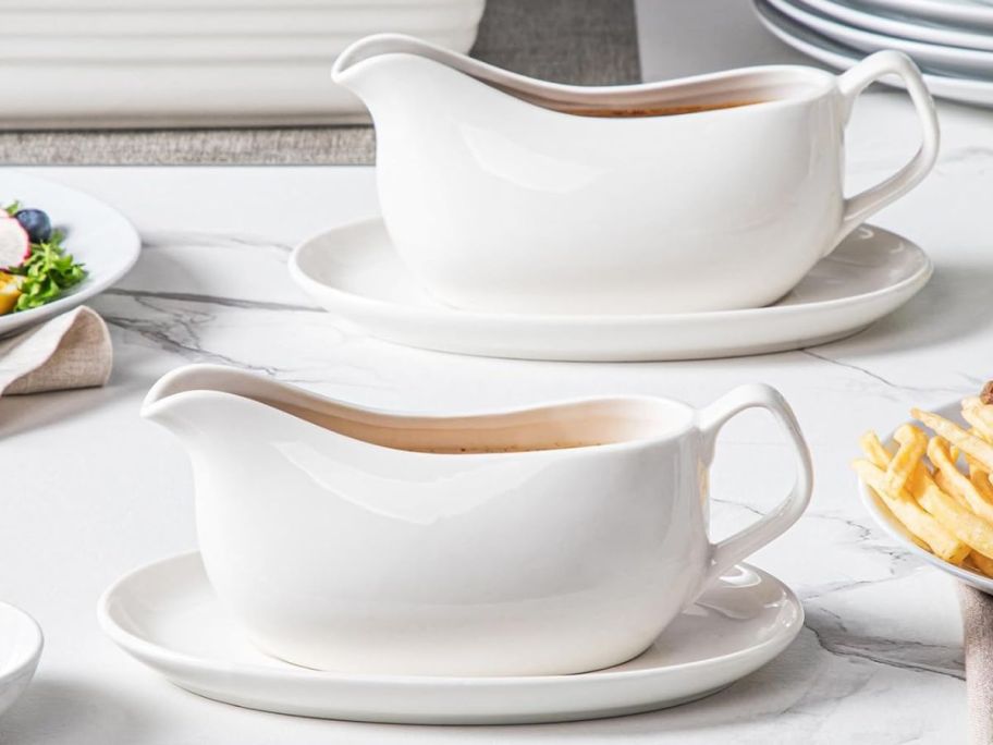 two different Gravy boat w saucers on top of the table