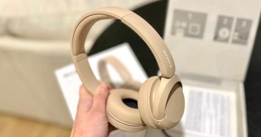 hand holding a pair of Sony wireless headphones