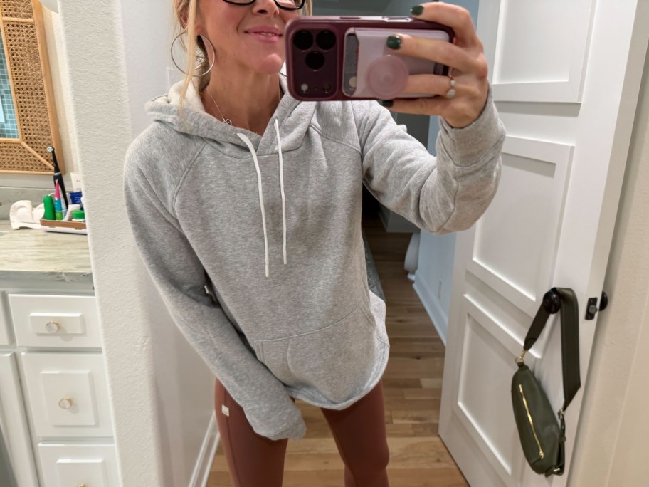 Collin (woman) wearing a grey hoodie and mauve leggings