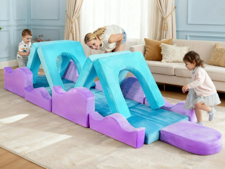 kids playing on a modular couch set up like an obstacle course with a woman watching them