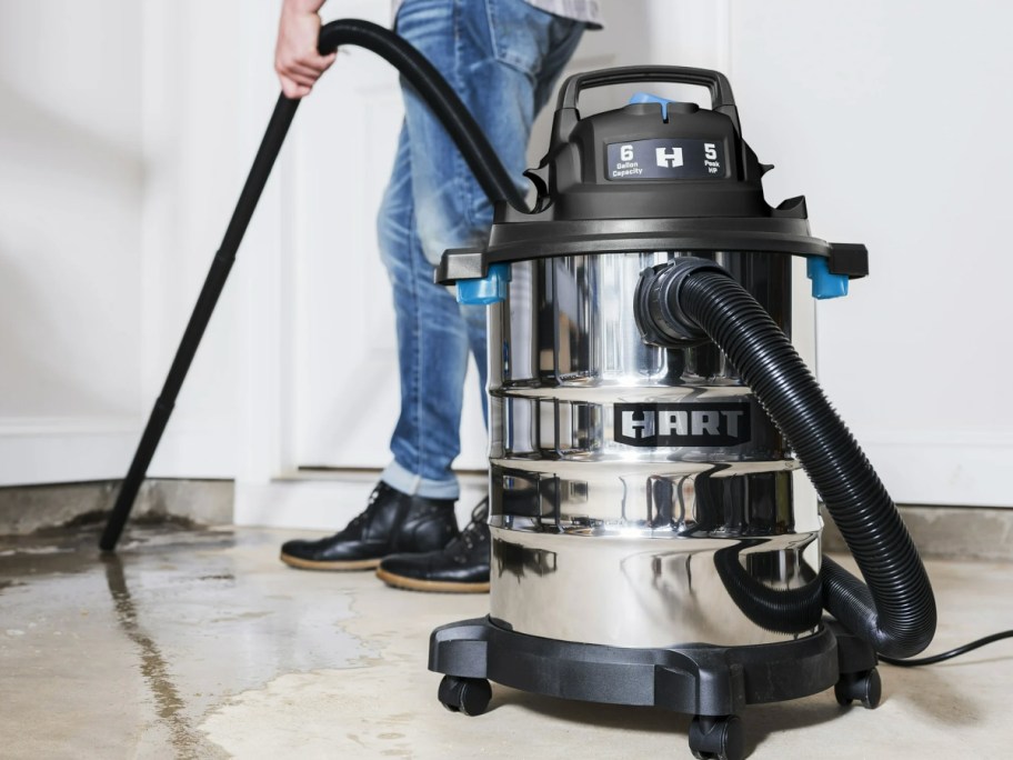 Man using hart stainless steel vacuum to vacuum water from concrete floor