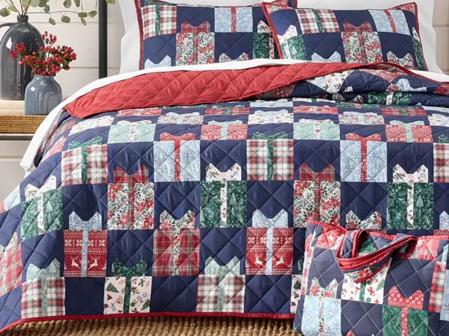 A quilt embroidered with presents on a bed 