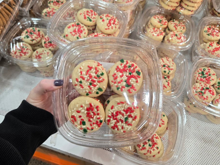 A hand holding up a container of holiday sprinkle cookies at Costco.