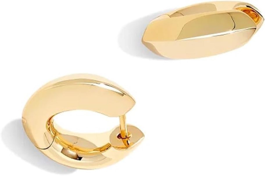 stock photo of gold huggie earrings on white background