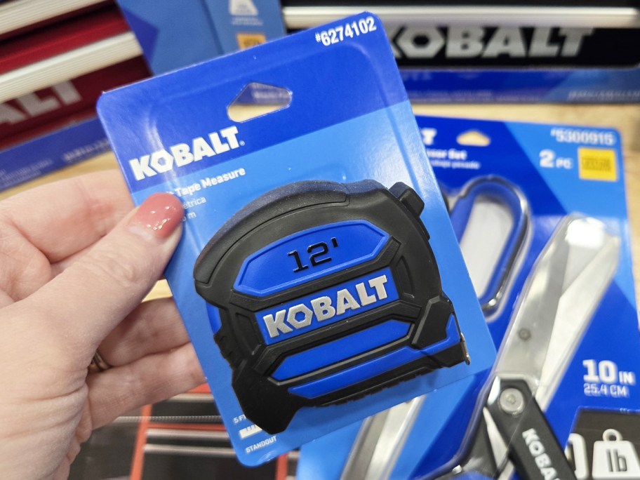 hand holding up a blue and black tape measure