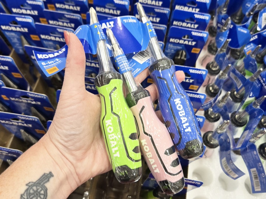 hand holding green, pink, and blue screwdrivers