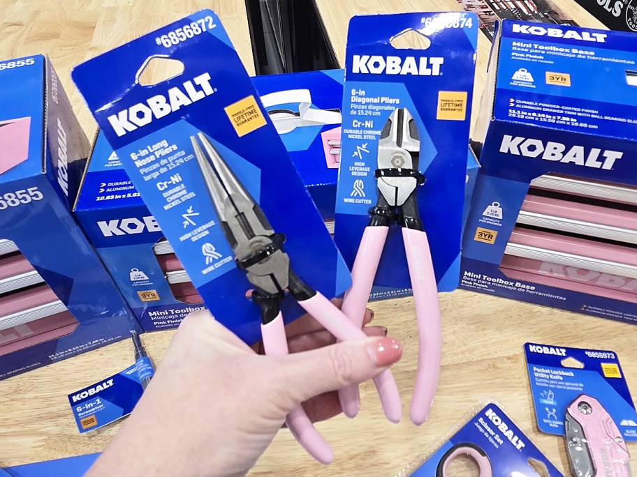 hand holding up two pairs of pink pilers in store