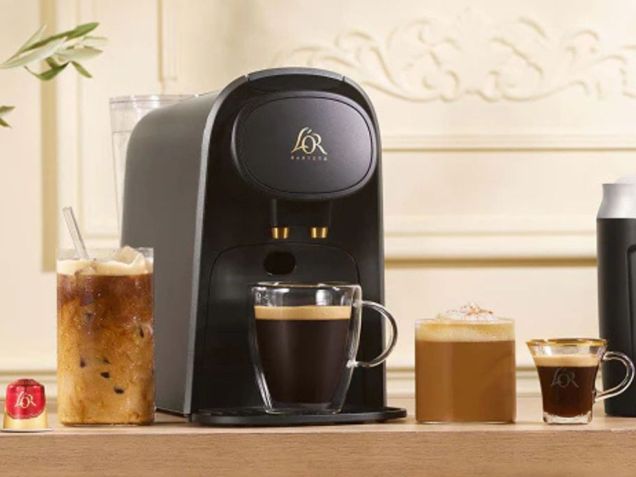 A coffee maker is placed on the counter, and coffee cups and glasses are placed around it. 