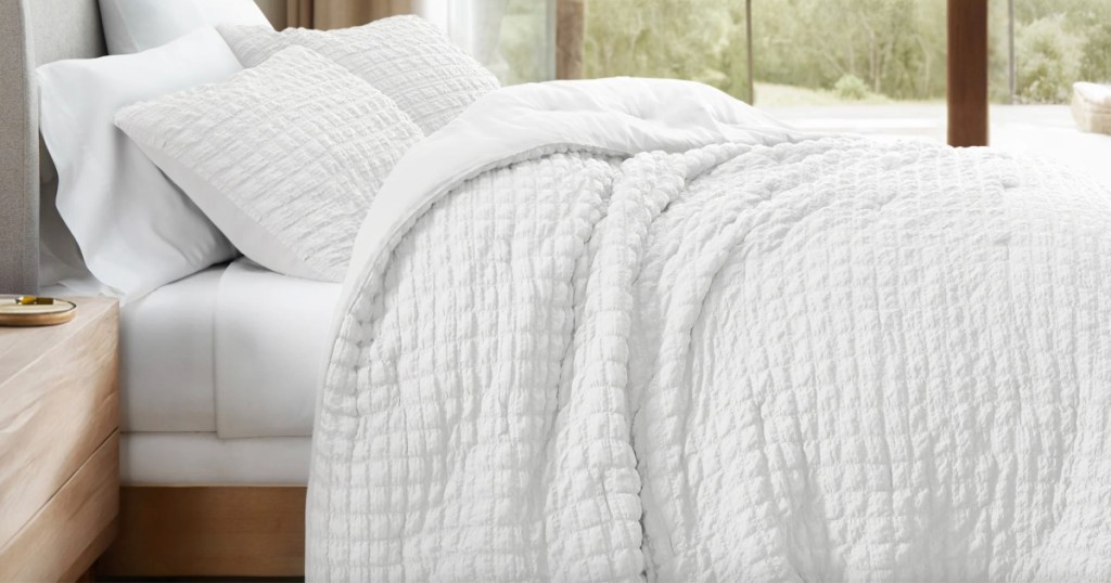 white textured comforter with shams on bed