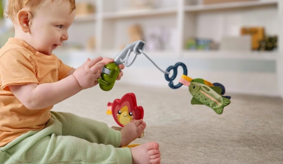 a baby playing with a pretend fishing pole reeling in a fish