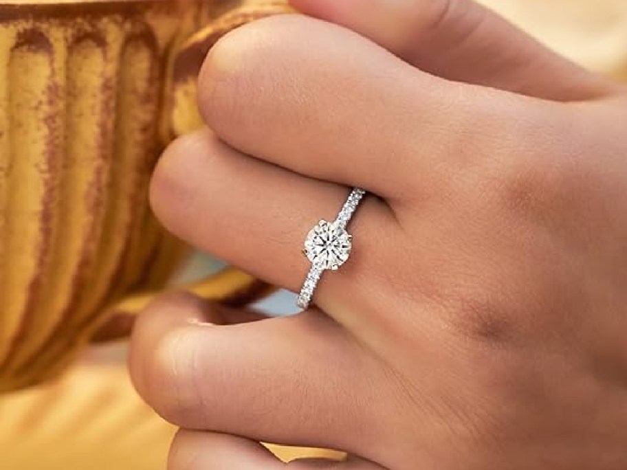 A hand wearing a moissanite ring.